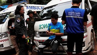 Image: Men standby near ambulances outside Tham Luang cave complex in the n