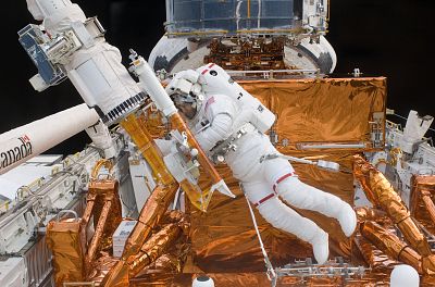 Astronaut Mike Massimino works with the Hubble Space Telescope in the cargo bay of the Earth-orbiting Space Shuttle Atlantis.