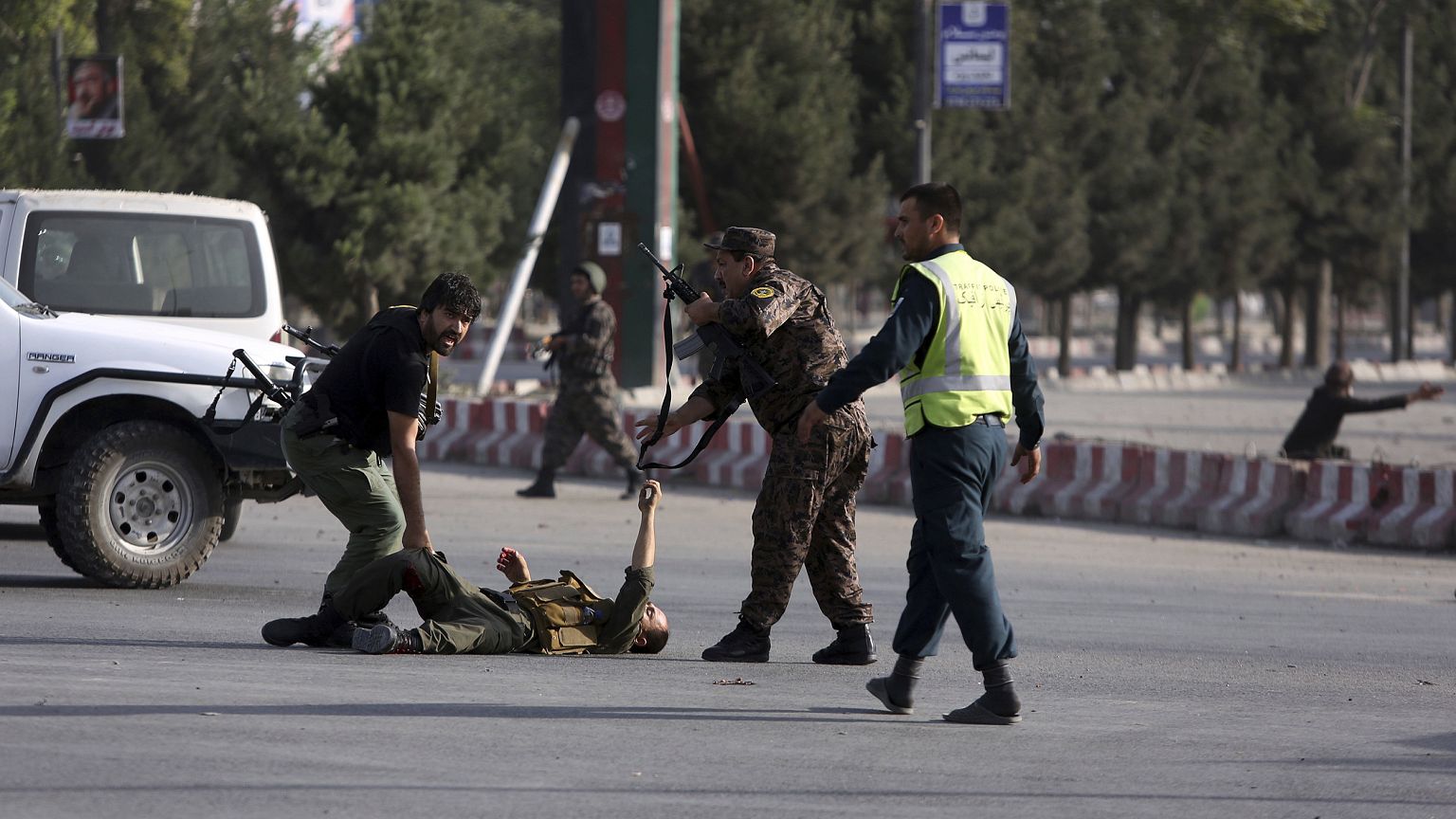Image: An injured security officer gets help as he lies on the ground after