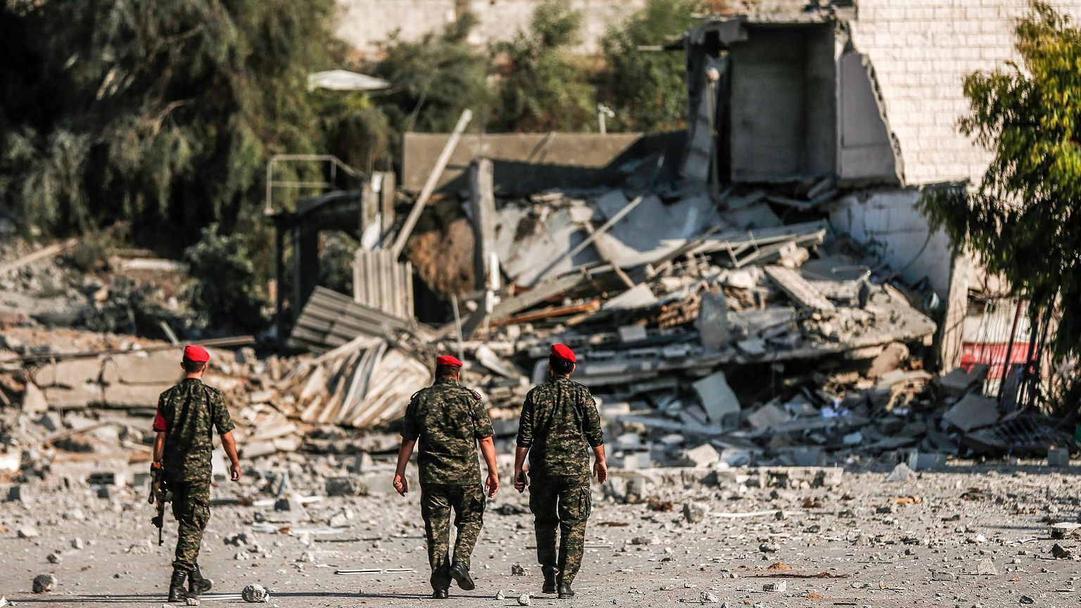 Image: Members of Hamas' military police walk through a site that was hit b