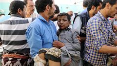 Image: A Yemeni man holds a boy who was injured by an airstrike in Saada