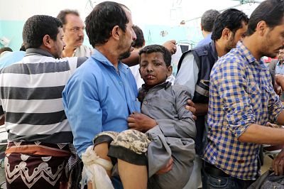 A Yemeni man holds a boy who was injured in the air strike on Thursday.