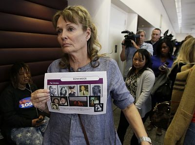 Melanie Barbeau displays photos of murder victims believed to be slain by the Golden State Killer as she leaves a hearing for suspect Joseph DeAngelo in Sacramento, California, on May 14, 2018. Claude Snelling is seen top left.
