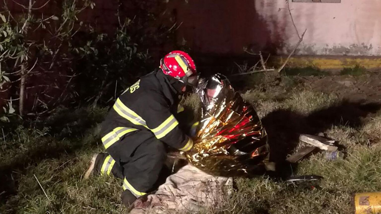 Image: A firefighter assists a victim following a bus crash along a road be