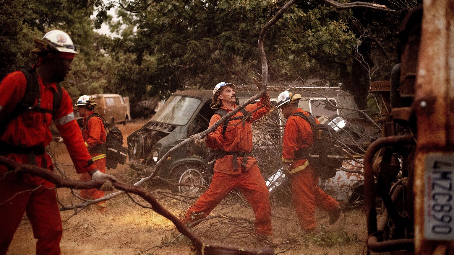 Inmate firefighters clear brush to create a fire break while battling the F