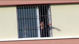 Deported migrants call for freedom from behind barred windows