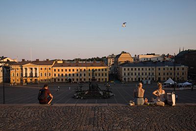 Tourists sit on steps looking out over Senate square as the sun sets in Helsinki, Finland, on July 16, 2018.