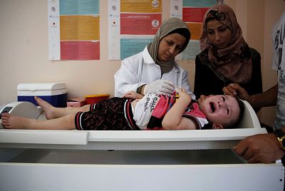A Palestinian child receives medical check ups and aid from the UNRWA\'s mobile team on the outskirts of Hebron on August 9, 2018.