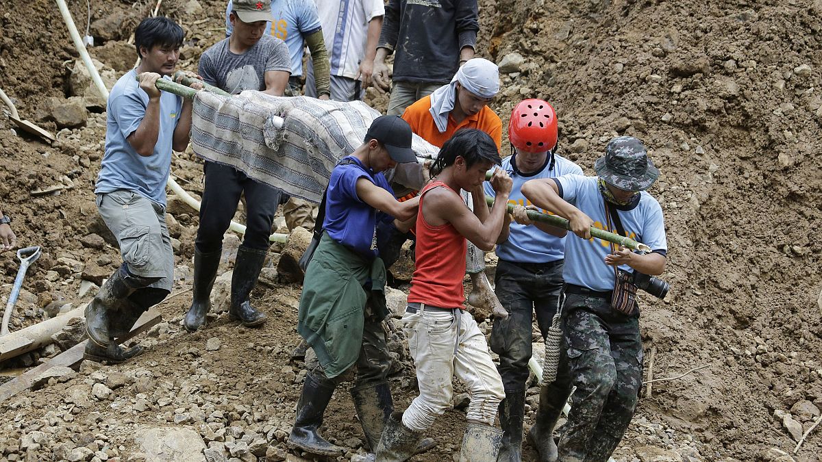 Image: Rescuers carry a body from the site where victims are believed to ha