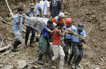 Image: Rescuers carry a body from the site where victims are believed to ha