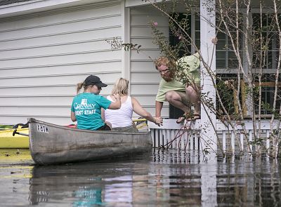 David Covington jumps from a porch railing to his canoe along with Maura Walbourne and her sister Katie Walborne in Conway, South Carolina, on Sept. 23, 2018. The three paddled a canoe to Covington\'s home on Long Avenue on Sunday to find it flooded and the floor boards floating.