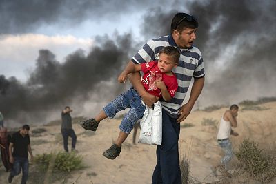 A Palestinian protester carries a boy as he runs from tear gas fired by Israeli soldiers during a protest in Beit Lahiya in the northern Gaza Strip on Sept. 10.