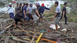 Image: Residents carry a bag containing the body of a tsunami victim in Pal