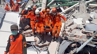 Image: A search and rescue team evacuates a victim from the ruins of the Ro