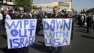 Image: Men hold up anti-American and anti-Israeli placards at a rally conde