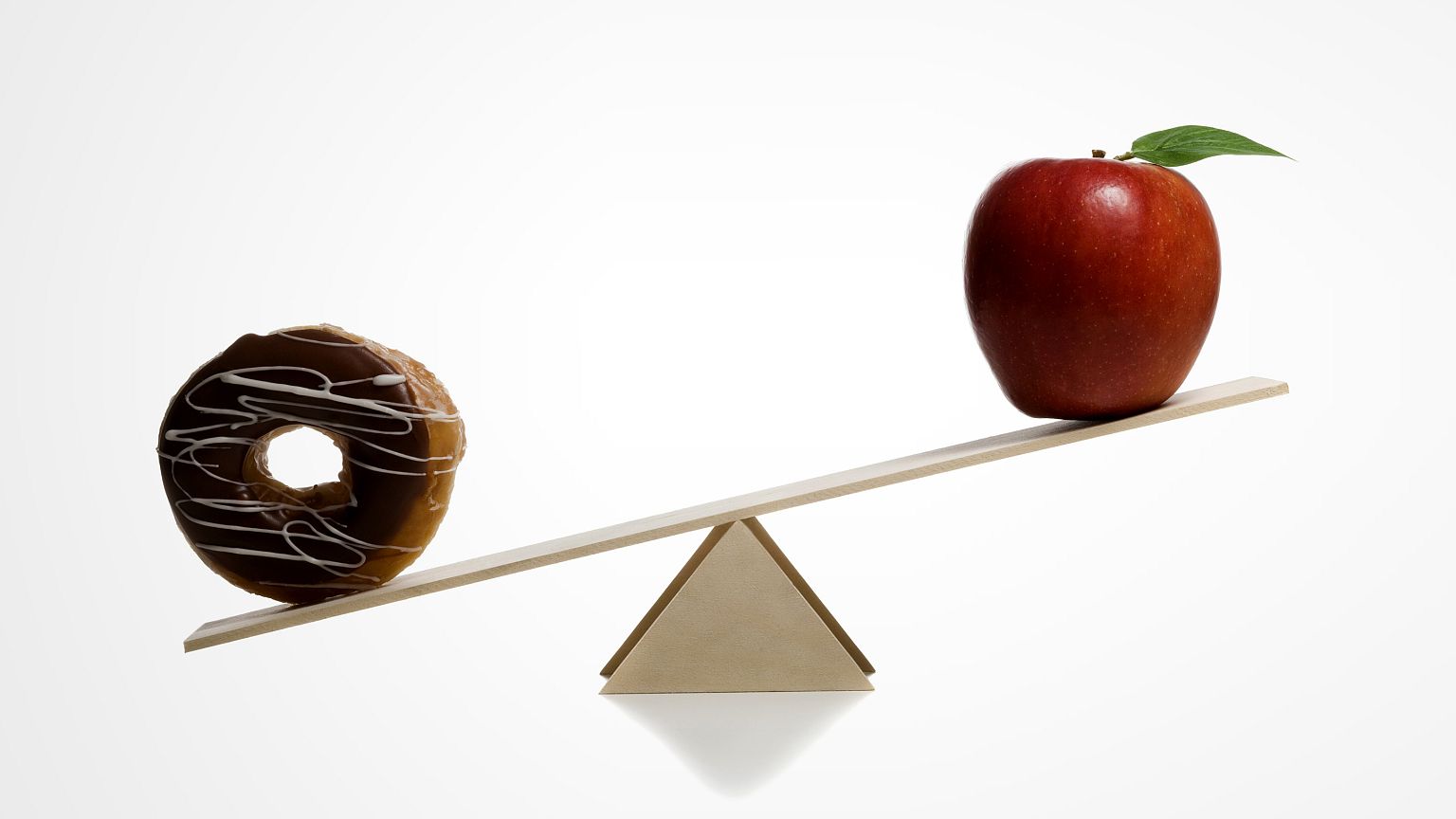 Close-up of a donut and an apple on a seesaw