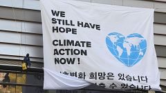 Image: Greenpeace activists display a big banner reading "We still have hop