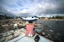 Image: A resident looks at a washed out boat in Wani