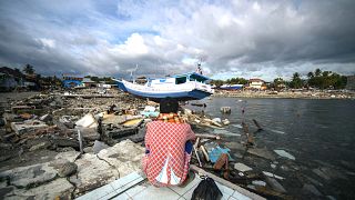 Image: A resident looks at a washed out boat in Wani