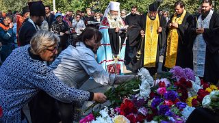 Image: People lay flowers for the victims during a church service in Kerch,