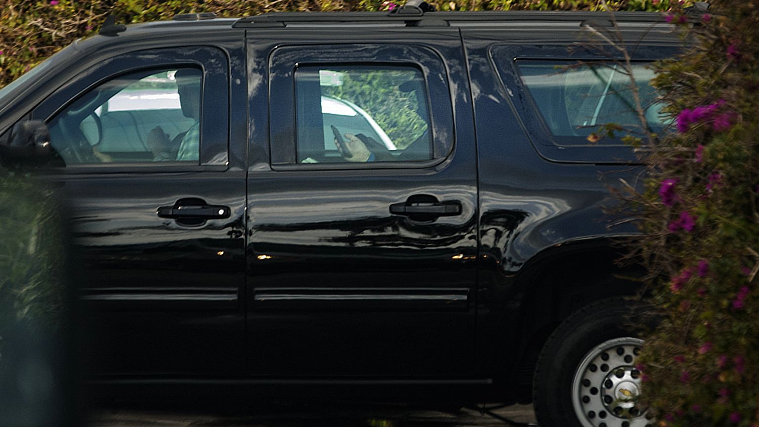 Image: President Donald Trump uses his phone as a motorcade departed his Ma