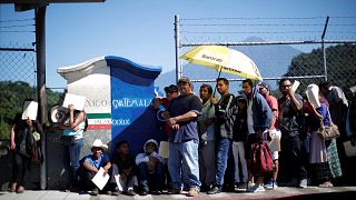 Image: Central American migrants queue at a border connecting Guatemala and