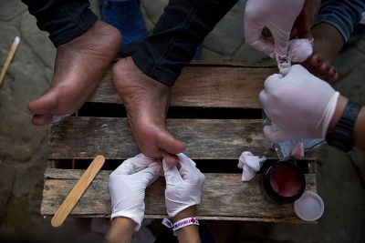 Volunteers from the Mexican Red Cross treat the blistered and cut feet of Central American migrants as a caravan of thousands stops for the night in Arriaga, Mexico, Friday, Oct. 26, 2018. Many migrants said they felt safer traveling and sleeping with several thousand strangers in unknown towns than hiring a smuggler or trying to make the trip alone.(AP Photo/Rebecca Blackwell)