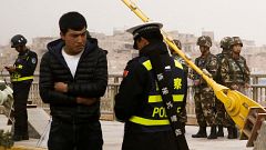 Image: A police officer checks the identity card of a man as security force