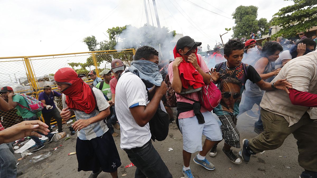Image: Migrants break the fence between Guatemala and Mexico and fight poli