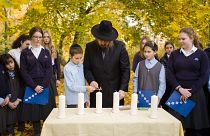 Rabbi Yehuda Teichtal lights candles with students during an event to mark