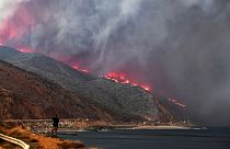 Image: A man watches as the Woolsey Fire reaches the ocean along Pacific Co