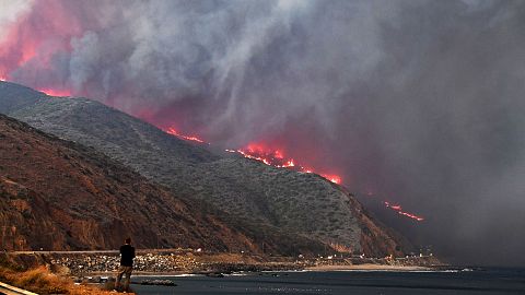 Image: A man watches as the Woolsey Fire reaches the ocean along Pacific Co