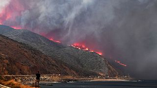 Image: A man watches as the Woolsey Fire reaches the ocean along Pacific Co