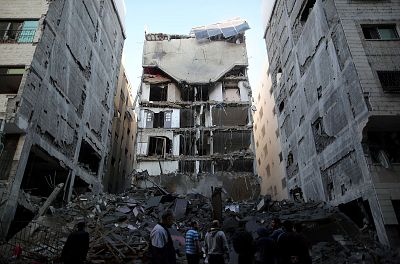 Palestinians gather near the remains of a building that was completely destroyed by an Israeli air strike, in Gaza City on Tuesday. 