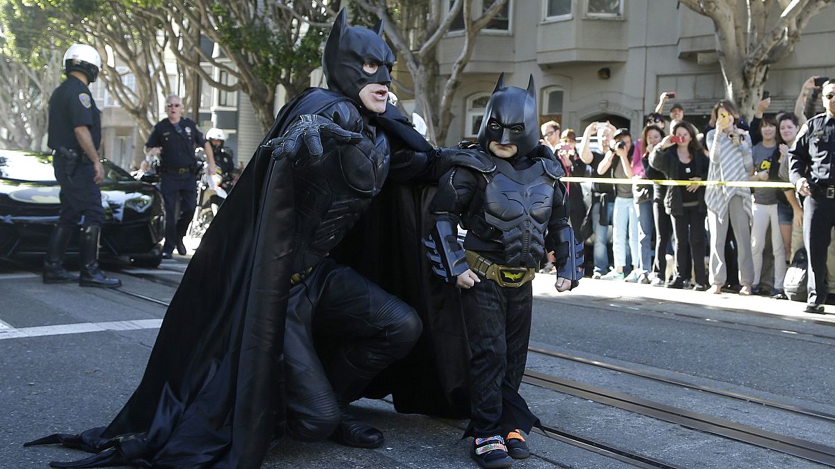Miles Scott, dressed as Batkid, walks with Batman before saving a damsel in