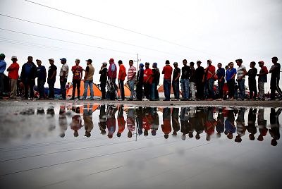 Migrants, part of a caravan of thousands traveling from Central America en route to the United States, stand in a line to receive cups of coffee in a makeshift camp at a gas station where the migrants wait for buses which take them to the Mexican border city of Tijuana, in Navojoa, Mexico November 16, 2018.