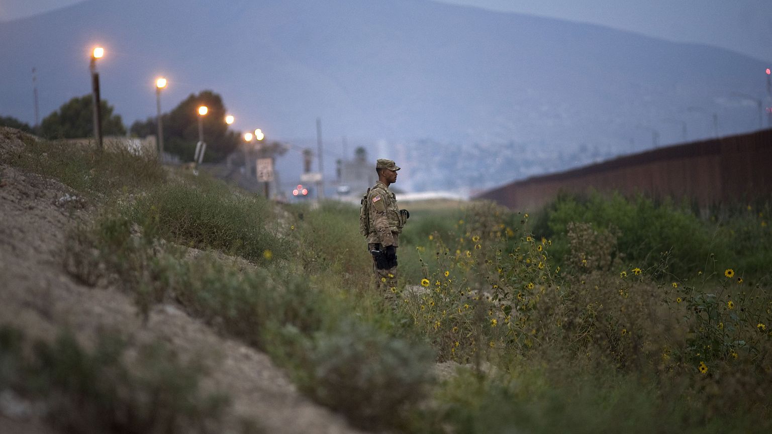 Image: A U.S. military policeman watches as other troops install concertina
