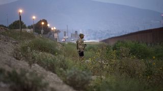 Image: A U.S. military policeman watches as other troops install concertina