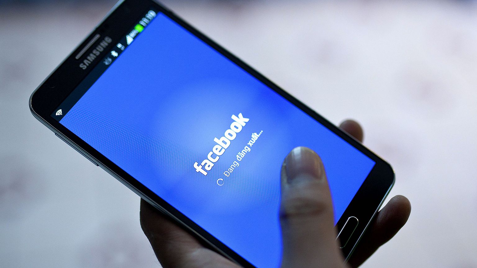 Image: 28 November 2013 shows a person using Facebook on his phone at a caf