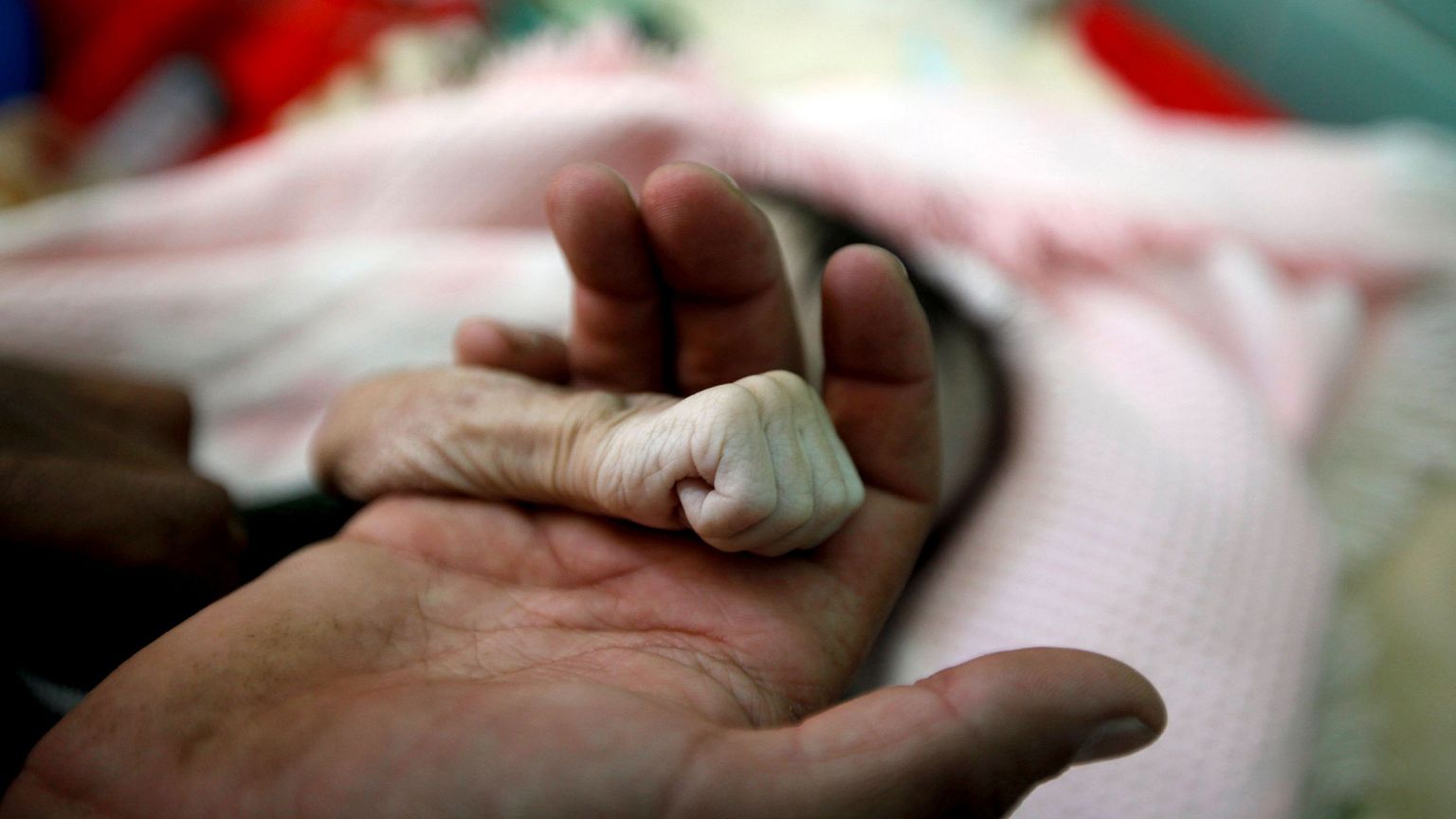 Image: Saleh Hassan al-Faqeh holds the hand of his four-month-old daughter,
