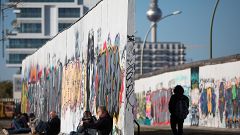 Image: People sit along the Berlin wall at the East Side Gallery in Berlin,