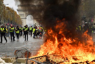 Protestors stand in front of a fire of furnitures during a protest of Yellow vests (Gilets jaunes) against rising oil prices and living costs near the Arc of Triomphe on the Champs Elysees in Paris on Nov. 24, 2018.