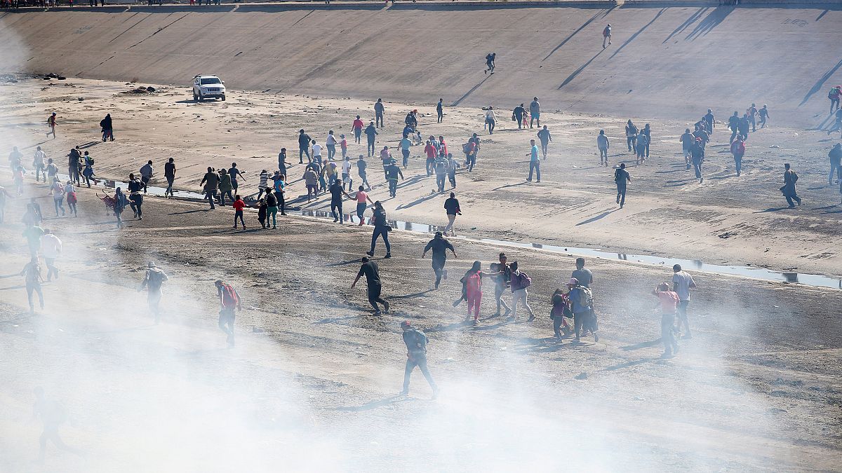 Image: Migrants run from tear gas, thrown by the U.S border patrol, near th