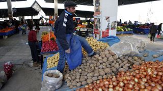 Image: A vendor sells potatoes and onions in an open market in central Anka