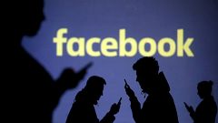 Image: Silhouettes of mobile users next to a screen projection of the Faceb