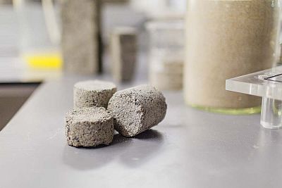 The bio-bricks are created through a natural process called microbial carbonate precipitation.