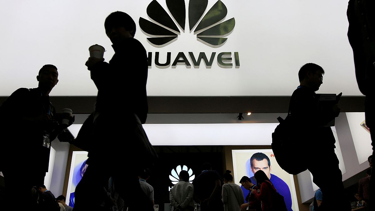 Image: People walk past a sign board of Huawei at CES Asia 2016 in Shanghai