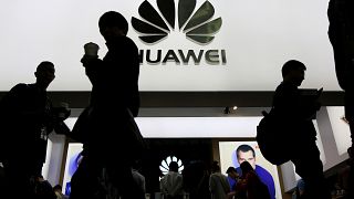 Image: People walk past a sign board of Huawei at CES Asia 2016 in Shanghai