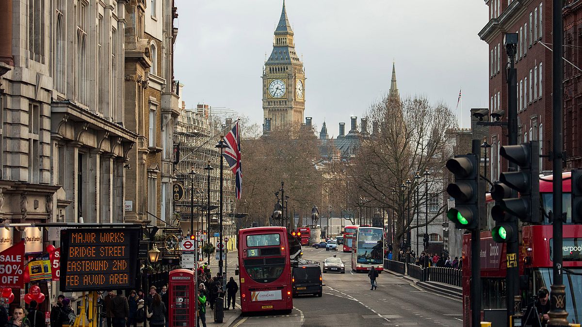 Image: Buses pass through traffic lights near the Houses of Parliament in L