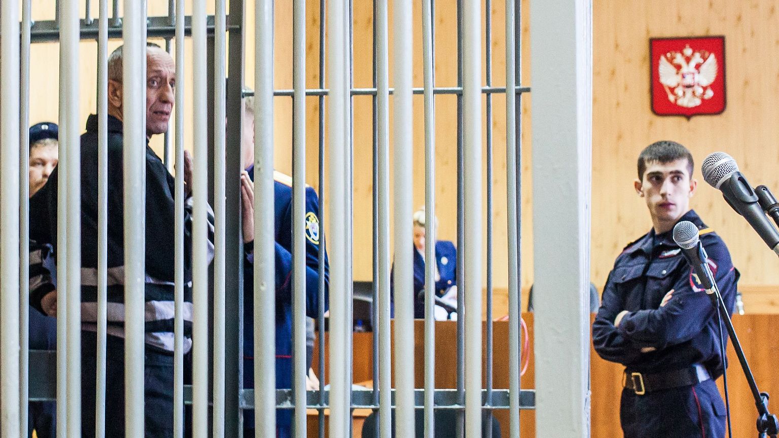 Mikhail Popkov stands inside a defendant's cage during a court hearing in I